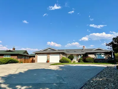 a large house with a driveway in front of it at Lake and the City Bed and Breakfast in West Kelowna