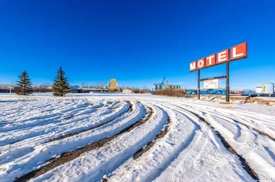 a snow covered road with a motel sign at Blue Horse Motel in Beiseker
