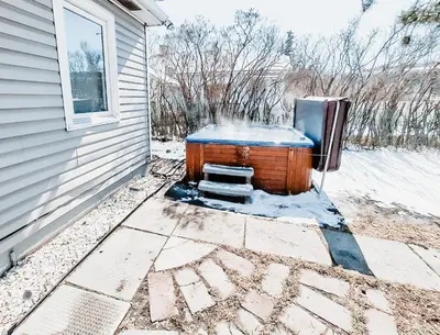 a hot tub sitting outside of a house in the snow at Stay & Play - Central Family Friendly in Calgary