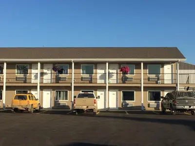 a large building with cars parked in a parking lot at Voyageur Motel in Rocky Mountain House