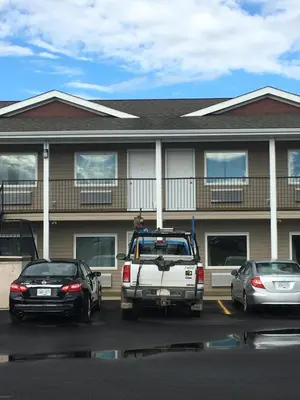 a white truck parked in a parking lot in front of a building at Voyageur Motel in Rocky Mountain House