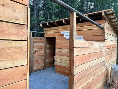 a wooden building with a gate and a patio at Butterfly Cottage - Glamping in Oliver