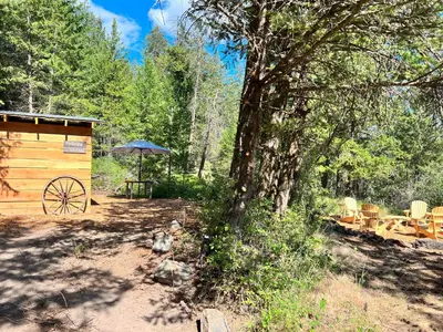 a wooden cabin with a table and chairs next to a tree at Butterfly Cottage - Glamping in Oliver