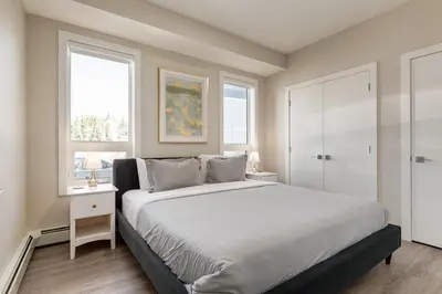 a bedroom with a large bed and two windows at Inner City Apartment, Pet Friendly, Free Underground Parking in Calgary
