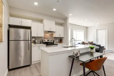 a kitchen with white cabinets and a stainless steel refrigerator at Inner City Apartment, Pet Friendly, Free Underground Parking in Calgary