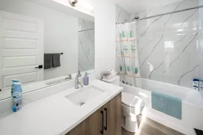 a white bathroom with a sink and a toilet at Near Downtown, Large 3BR! FREE Banff Pass in Calgary