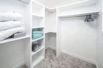 a white closet with white shelves and towels at Near Downtown, Large 3BR! FREE Banff Pass in Calgary