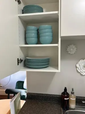 a kitchen cabinet with blue dishes in it at Garden Suite in Colwood in Victoria