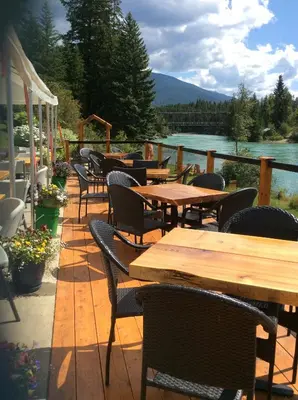 a row of tables and chairs on a deck with a lake at Tete Jaune Lodge in Tete Jaune Cache