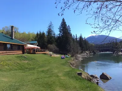 a log cabin next to a river next to a house at Tete Jaune Lodge in Tete Jaune Cache