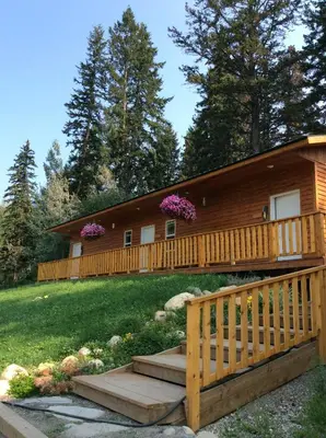 a log cabin with a staircase leading to a house at Tete Jaune Lodge in Tete Jaune Cache