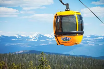 a yellow cable car flying over a mountain at BigWhite Ski In-Out Chalet w Priv HotTub & Garage in Big White