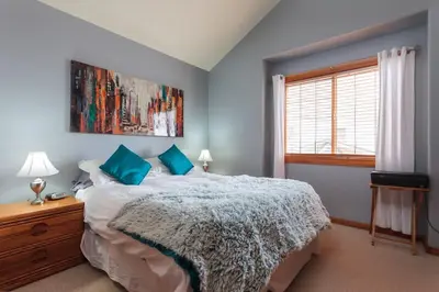 a bedroom with a bed with blue walls and a window at BigWhite Ski In-Out Chalet w Priv HotTub & Garage in Big White