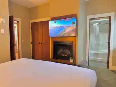 a bedroom with a bed with a fireplace and a tv at C111 Canmore World Class Solara Resort - Hot tub, Pool, Gym, AirCon, Free Parking & Netflix in Canmore
