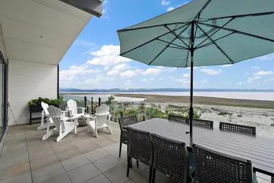 a patio with a table and chairs and an umbrella at Saratoga Beachfront Villa in Oyster Bay