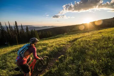 a woman riding a bike on a grassy hill at Powder Heights #25 home in Sun Peaks