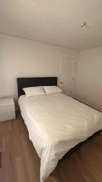a bedroom with a white bed and a white wall at Kevin Calgary Beddington Home in Calgary