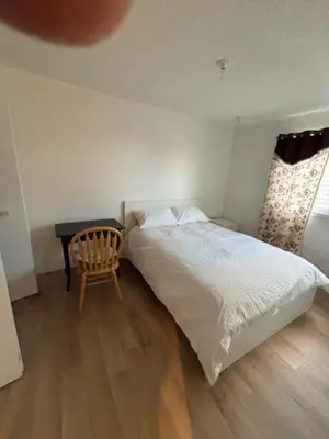 a bedroom with a bed and a chair and a window at Kevin Calgary Beddington Home in Calgary