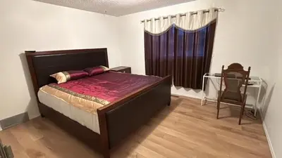 a bedroom with a large bed and a chair at Kevin Calgary Beddington Home in Calgary