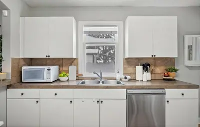 a kitchen with white cabinets and a sink and a microwave at Sylvan Lake Nook Family-Friendly and Close to Beach in Sylvan Lake
