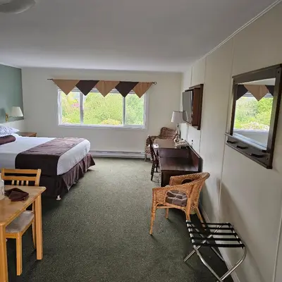 a bedroom with a bed and a desk and a window at Pacific Rim Motel in Ucluelet