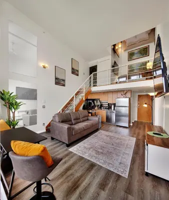an open living room with a couch and a staircase at Two-Story Loft with a High-rises view and Rooftop Deck in Vancouver