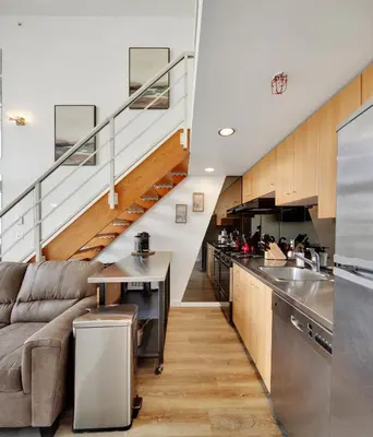 a living room with a couch and a kitchen at Two-Story Loft with a High-rises view and Rooftop Deck in Vancouver