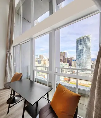 a living room with a table and chairs and a large window at Two-Story Loft with a High-rises view and Rooftop Deck in Vancouver