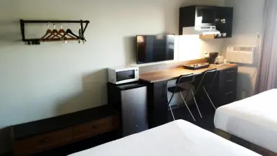 a hotel room with a desk with a television at Home Away Inn in Drayton Valley