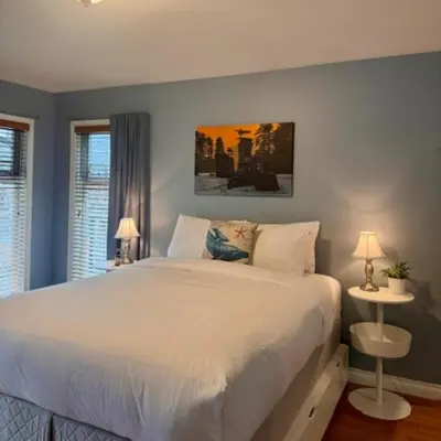 a bedroom with a large white bed with two lamps at Salal Forest - 2 bedroom cabin in the forest in Tofino
