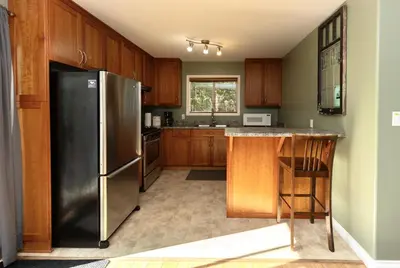 a kitchen with a stainless steel refrigerator and wooden cabinets at Salal Forest - 2 bedroom cabin in the forest in Tofino