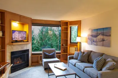 a living room with a couch and a fireplace at 1BR next to slopes on Blackcomb w pool & hot tub in Whistler