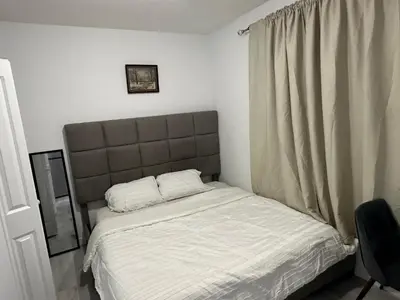 a bedroom with a bed and a window with white sheets at Muaysh Cozy Family suite - Londonderry Mall in Edmonton