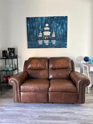 a brown leather couch sitting in a living room at Westshore Garden Escape in Victoria