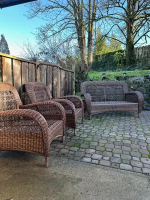 a group of wicker chairs and a couch on a patio at Westshore Garden Escape in Victoria