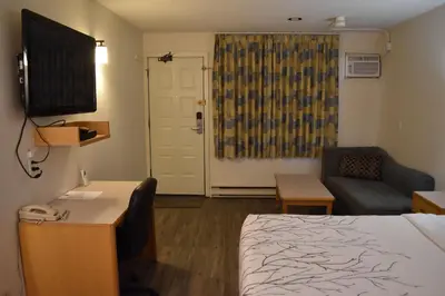 a hotel room with a bed and a desk and a television at Canadas Best Value Inn & Suites-Castlegar in Castlegar