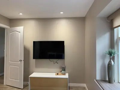 a living room with a tv on the wall at The Scandinavian House by Maple Dream Homestay- near Sky train in Vancouver