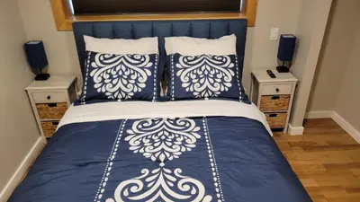 a bed with blue and white sheets and pillows at The Suite Treat in Whitehorse