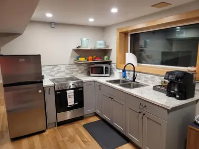 a kitchen with a stainless steel refrigerator and a sink at The Suite Treat in Whitehorse
