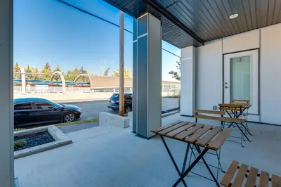 a porch with a bench and a car in a parking lot at Pet Friendly 2 Bed Close to Downtown in Calgary