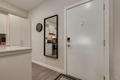 a white kitchen with a mirror and a clock at Pet Friendly 2 Bed Close to Downtown in Calgary
