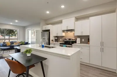 a kitchen with white cabinets and a table and a dining room at Pet Friendly 2 Bed Close to Downtown in Calgary