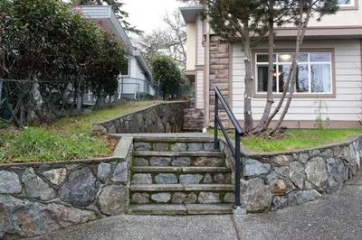 a stone retaining wall in front of a house at 2 BR Spacious Ground Level Suite in Victoria