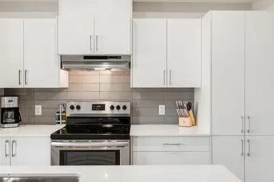 a kitchen with white cabinets and a stove top oven at Pet Friendly, Free Parking, Close to Downtown in Calgary