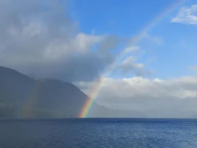 a rainbow in the sky over the water at Ocean's Edge in Port Alice