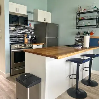 a kitchen with a counter and two stools in it at High Tide - Waterfront bachelor in Tofino
