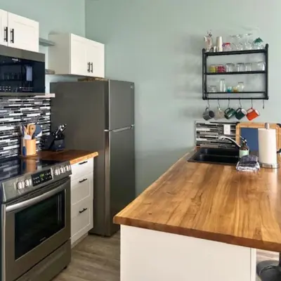 a kitchen with a stainless steel refrigerator and a wooden counter top at High Tide - Waterfront bachelor in Tofino