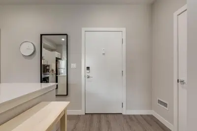 a white kitchen with a door and a mirror at Free Underground Parking, Pet Friendly Apartment in Calgary