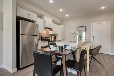 a kitchen with a table with chairs and a refrigerator at Free Underground Parking, Pet Friendly Apartment in Calgary