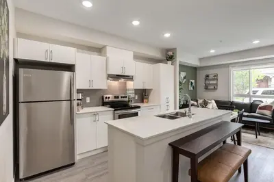 a kitchen with white cabinets and a stainless steel refrigerator at Free Heated Parking, Quick DT Access in Calgary